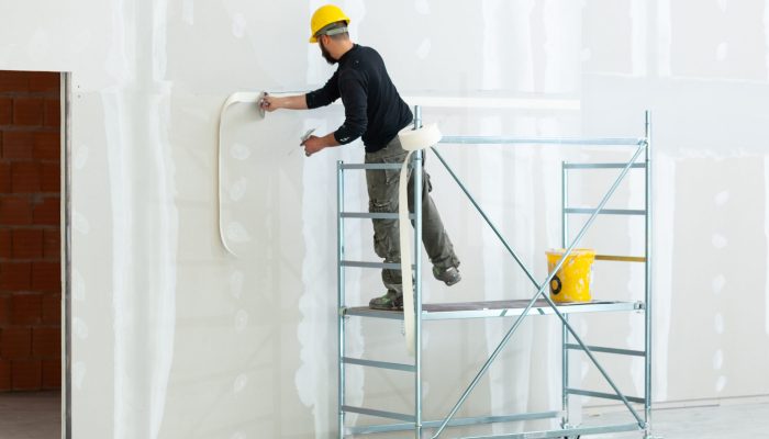 worker plastering gypsum board wall.